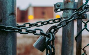Hek met een zware ketting en een hangslot, als beeld voor afhankelijkheid van leveranciers en digitale autonomie in het onderwijs