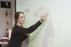 Leraar schrijft op een digibord in de klas, beeld bij de digicoach in het onderwijs